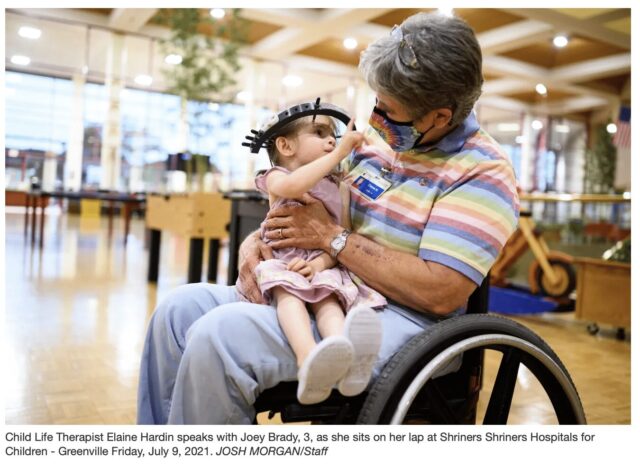 woman in wheel chair holding child in head brace