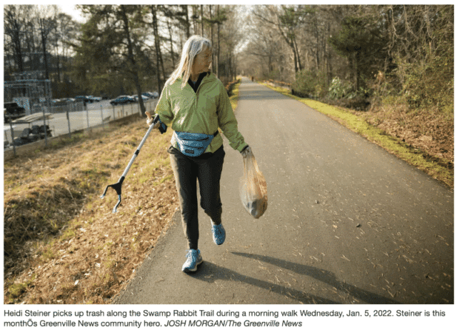 woman picking up garbage wearing a green jacket