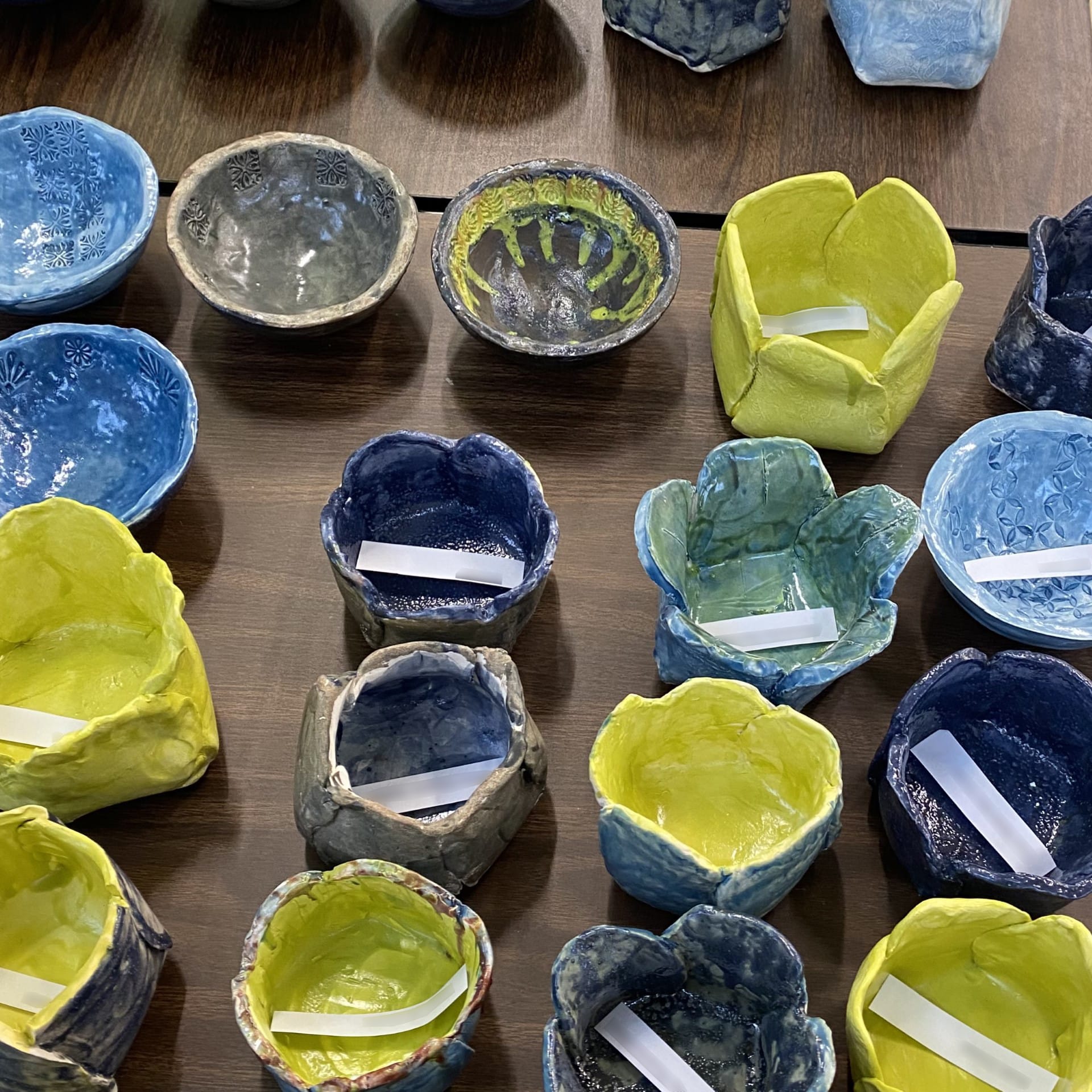 Colorful ceramic bowls crafted by students, featuring blue and green tones, showcasing Sarah Jones' empowering art project.