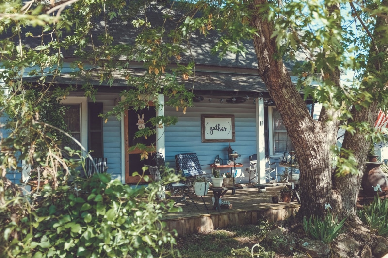 Charming blue house with a green garden, inviting porch for your house hunting journey. Key terms to know before buying.