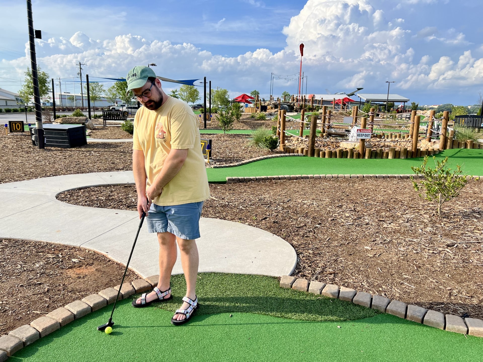 Man playing mini golf on a sunny day at an outdoor course, perfect for affordable summer family adventures.
