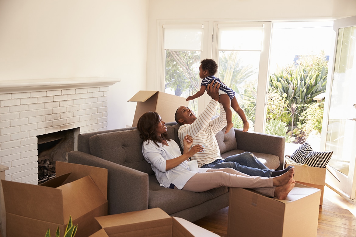 Family relaxes on sofa with son amidst moving boxes, understanding the closing costs of their new home.