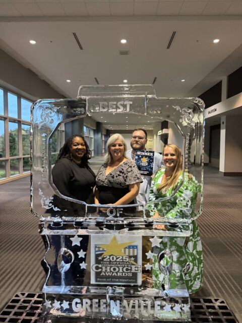 four people smiling inside of an ice scuplture frame