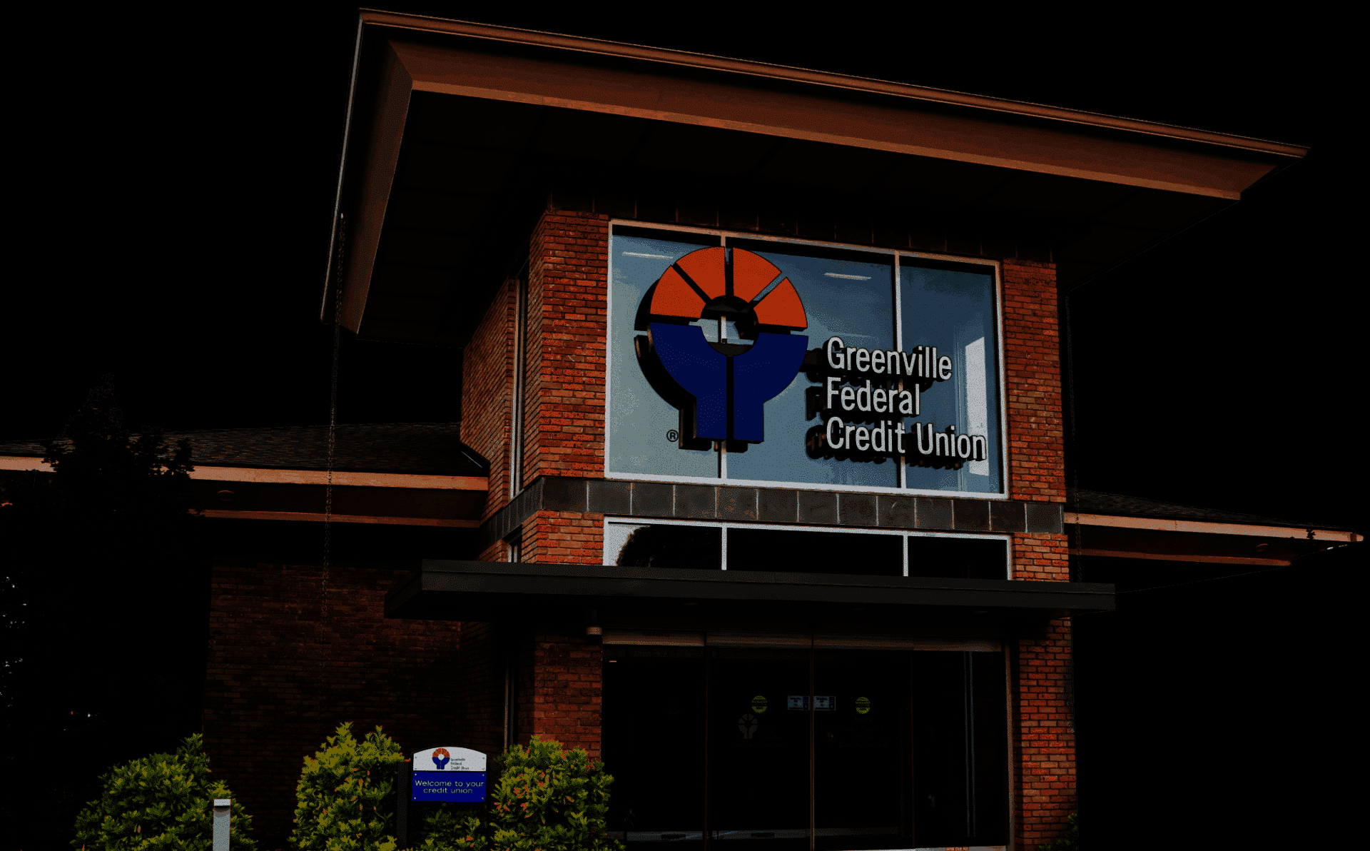 Greenville Federal Credit Union building with logo, highlighting better rates, community support, and voting rights.