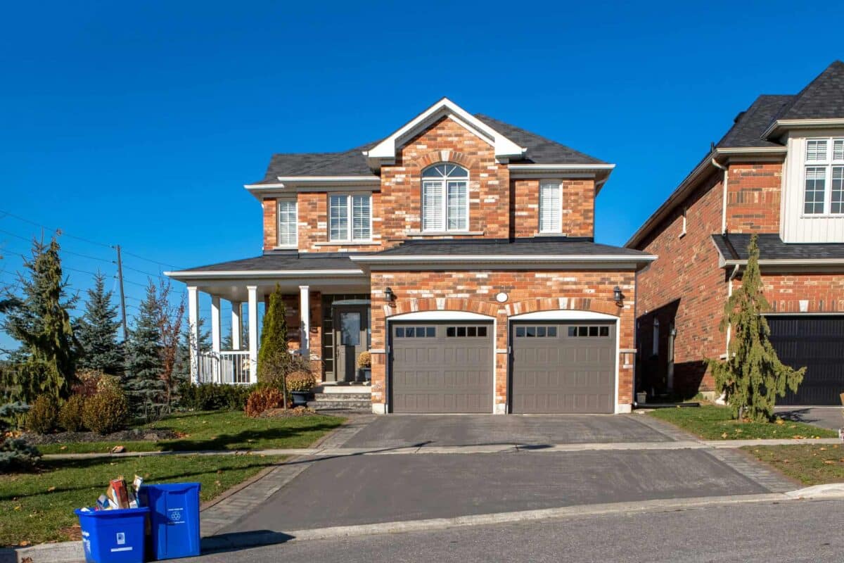 Brick house with two garages, manicured lawn, and recycling bins, illustrating mortgage options under 90% LTV.