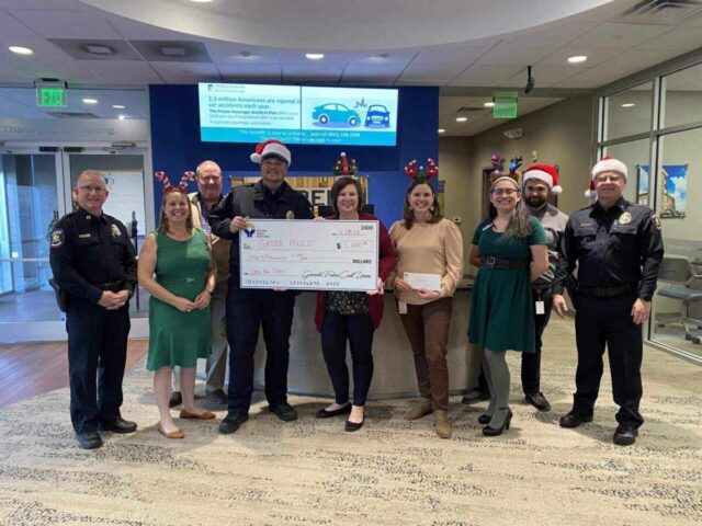 Greenville Federal Credit Union presents $1,000 check to Greer Police for Cops for Tots, enhancing community well-being.