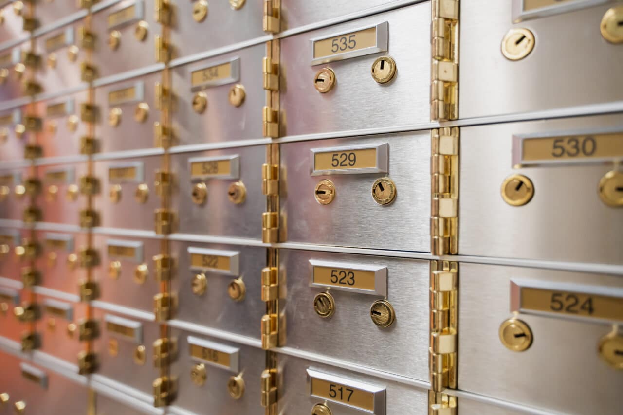Rows of secure safety deposit boxes with golden locks and individual numbering, available in multiple sizes.