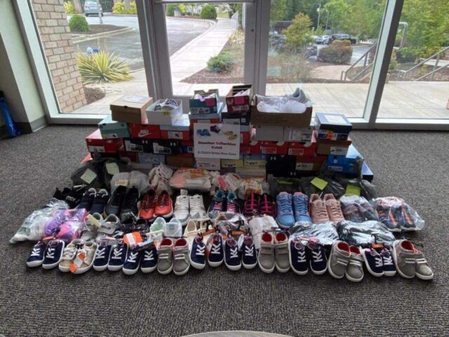 Collection of colorful shoes and boxes in a lobby for Greenville Federal Credit Union charity drive promoting community well-being.