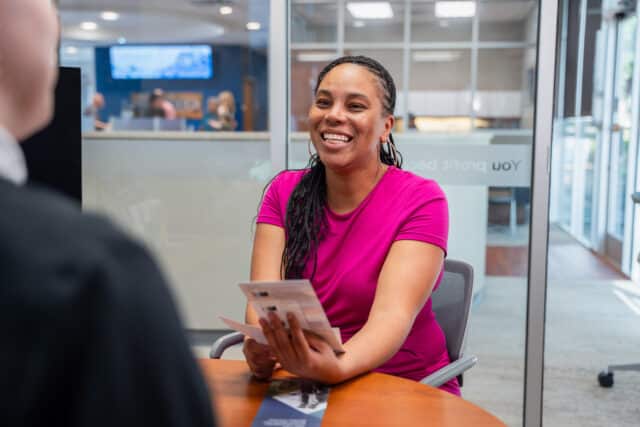 Smiling woman at Greenville Federal Credit Union discusses personalized banking services with a member.