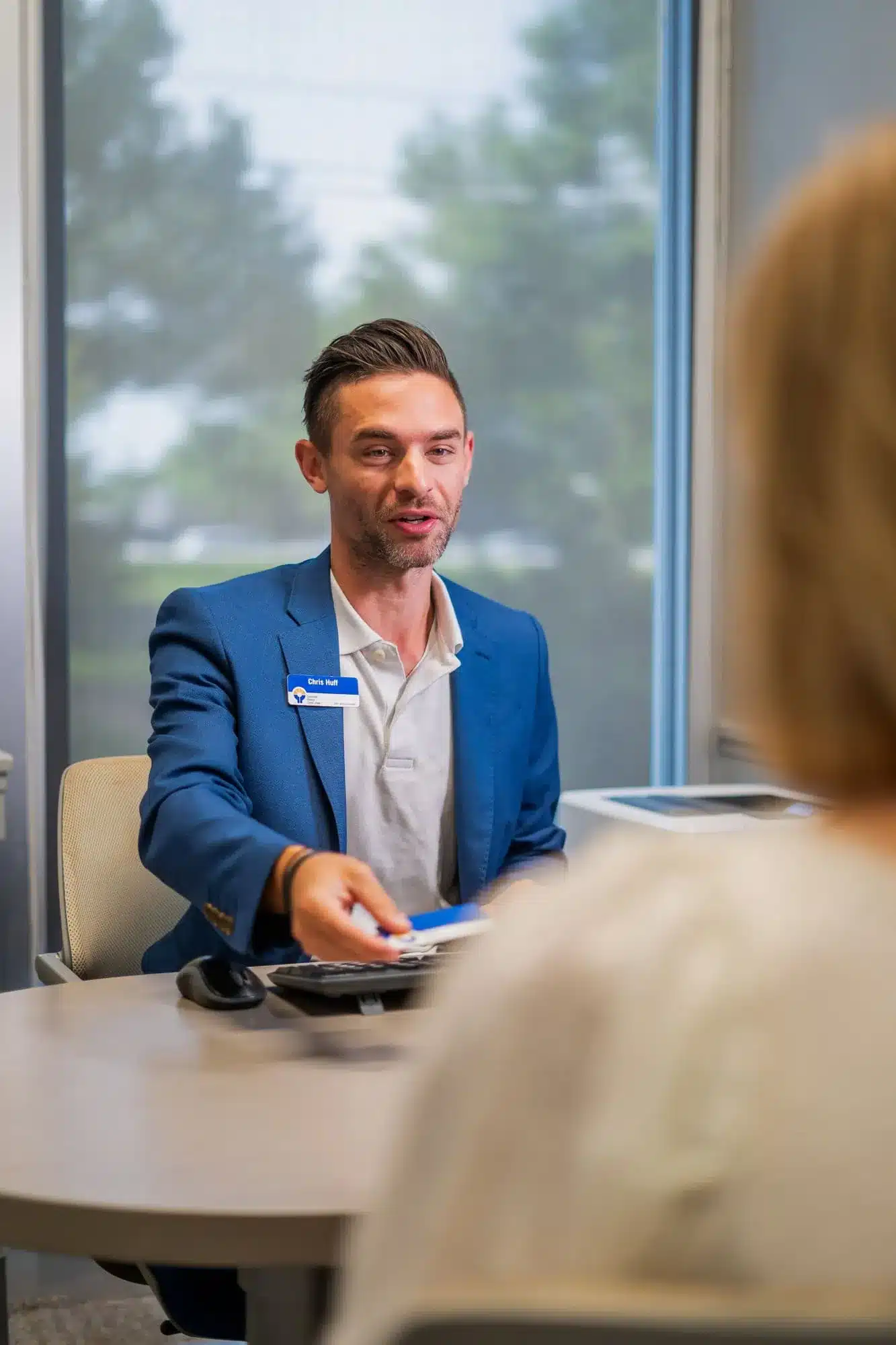 Bank representative in a blue suit assisting a customer at Greenville Federal Credit Union office.