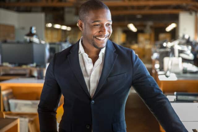 Smiling man in a suit in an office setting, representing prompt, confidential treasury management services.