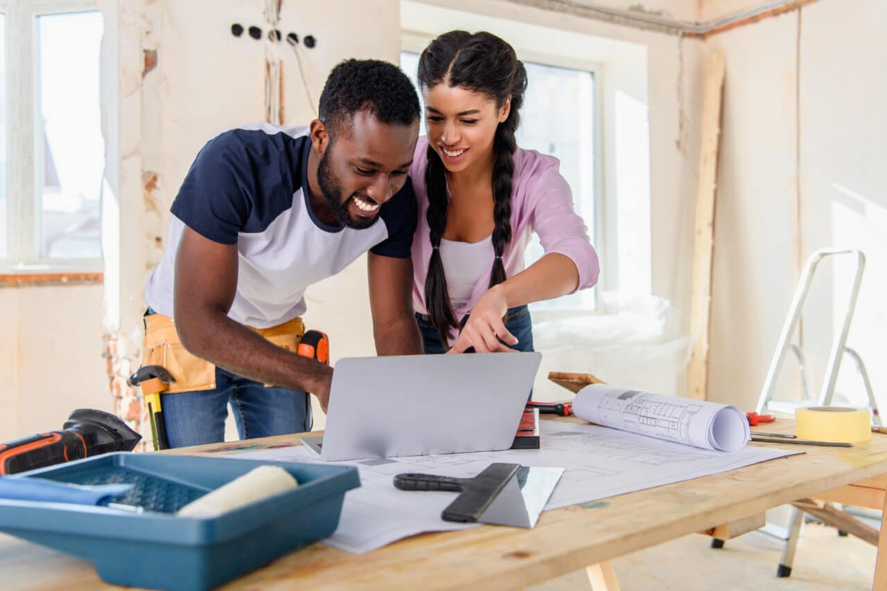 Couple looking at laptop during home renovation, discussing home equity loans to access funds for projects.