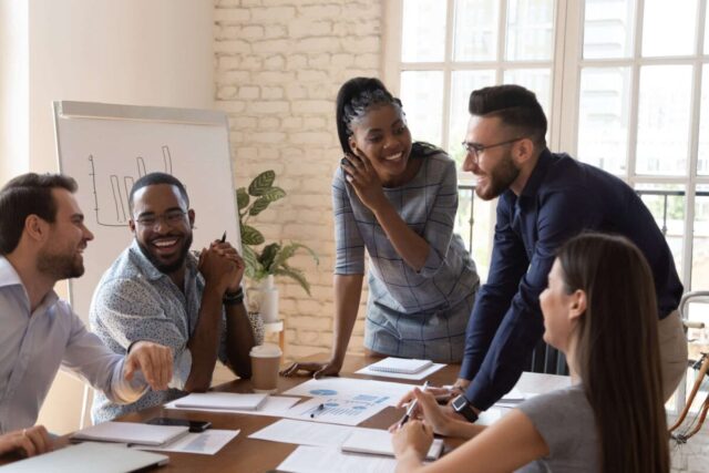 Cheerful diverse business team collaborates at a table, enhancing efficiency with strategic payables solutions.