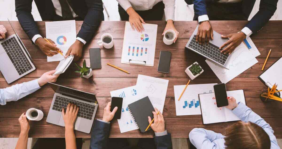 Business team discusses receivables solutions, using laptops and charts to streamline payment processing.