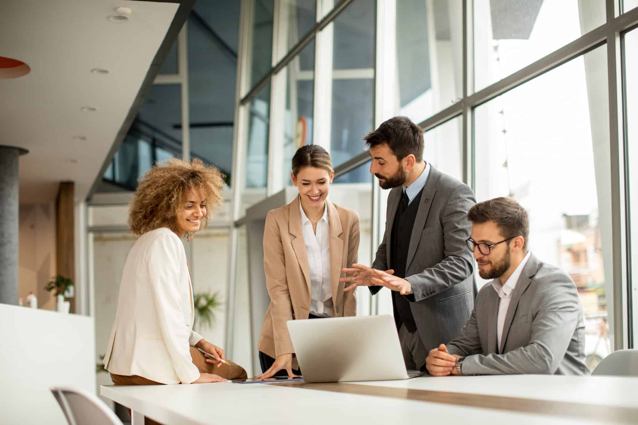 Multiethnic team collaborating on payment processing solutions around a laptop in a modern office.