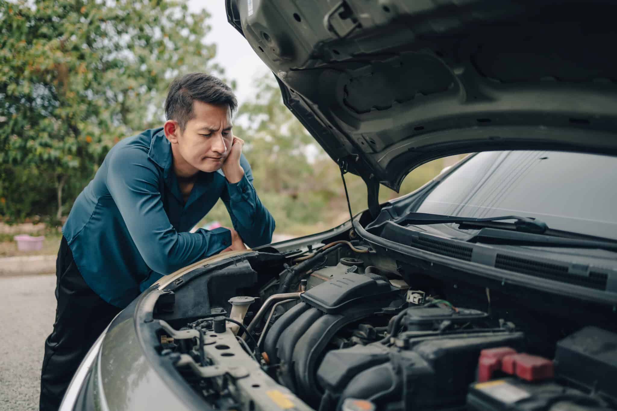 Man looks at car engine on roadside, contemplating loan insurance to protect finances and coverage options.