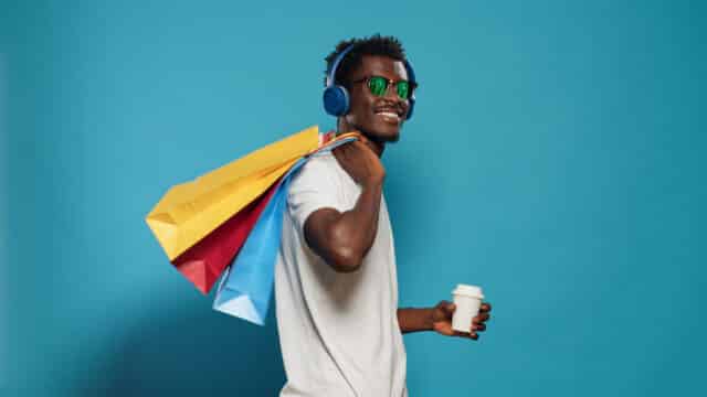 Cheerful man with shopping bags and headphones enjoys Black Friday deals, highlighting benefits of Kasasa Cash Checking.