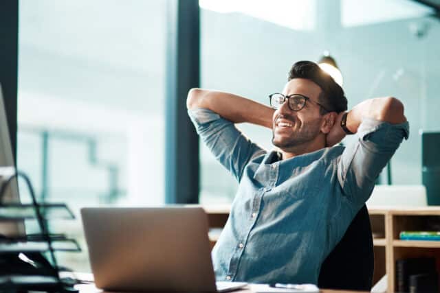 Young businessman in a modern office, relaxing and smiling after investing in share term certificates.