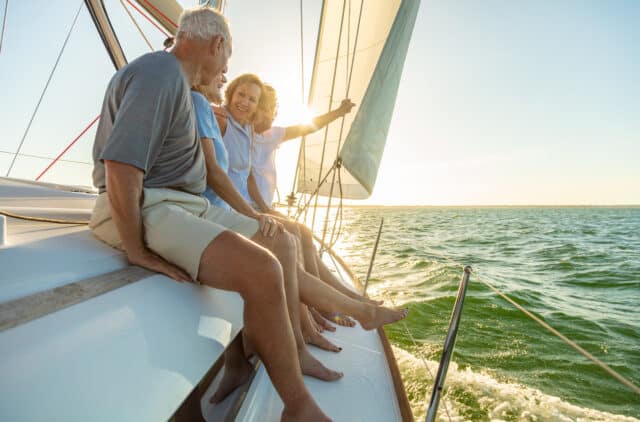 Senior friends enjoy sailing on a luxury yacht, embodying retirement freedom and maximizing savings benefits.