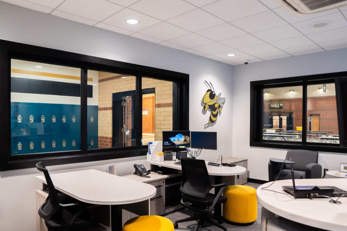 Modern office setup at Greer High with desks, monitors, and a bee mascot wall art, enhancing student banking internships.