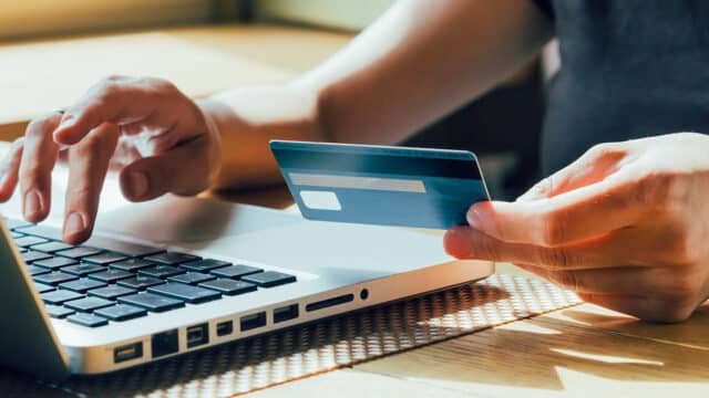 Woman uses laptop and credit card for secure online bill pay, featuring easy payments in Puerto Rico.
