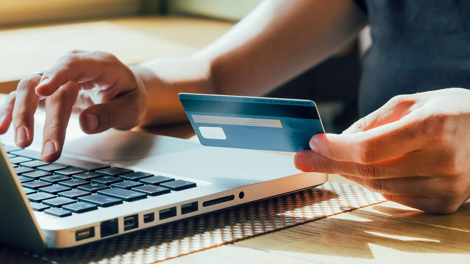 Woman uses laptop and credit card for secure online bill pay, featuring easy payments in Puerto Rico.