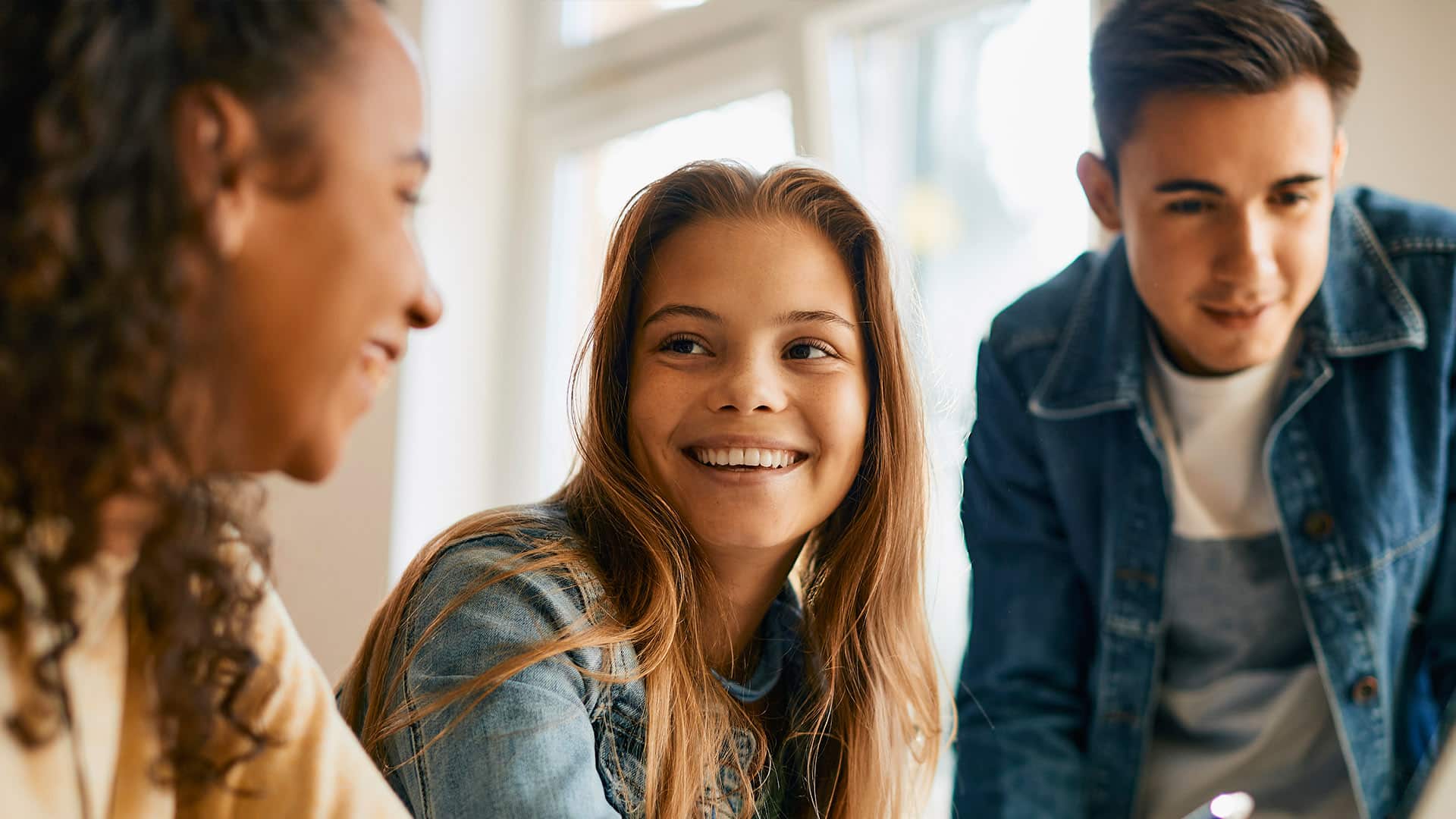 Happy high school students engage in e-learning, promoting smart money habits with Greenville Federal Credit Union youth accounts.