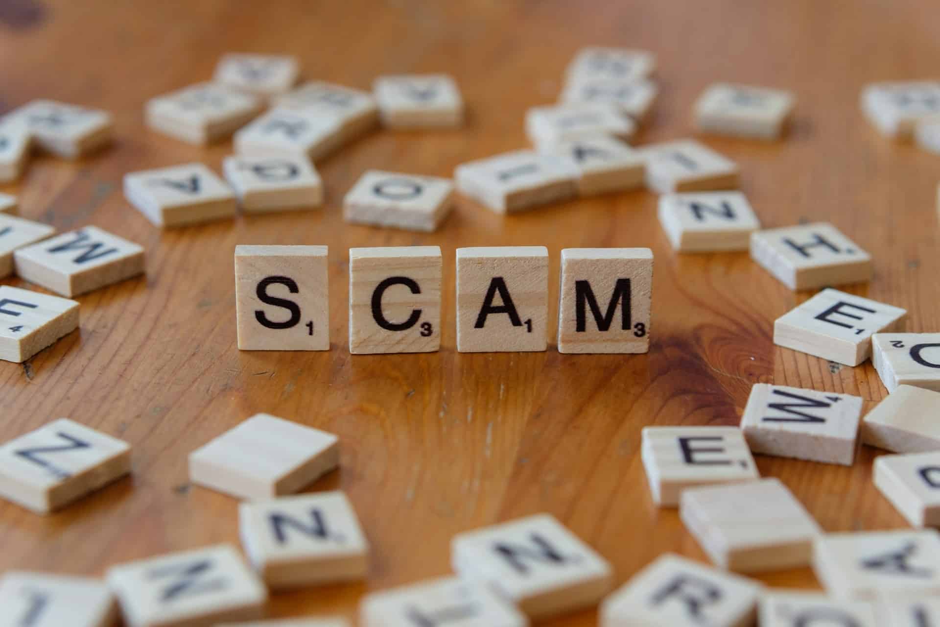 scrabble tiles that spell out "scam."